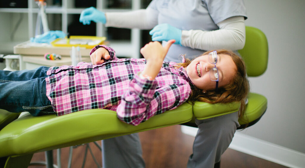 Girl smiling with braces in an orthodontic chair